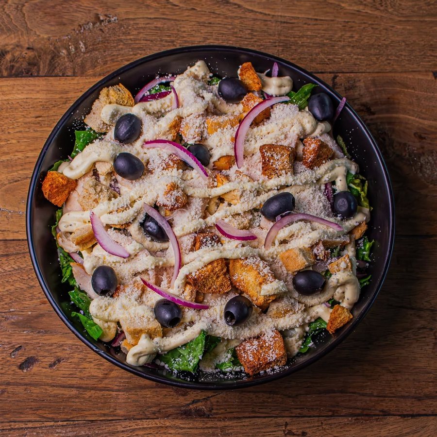 A salad bowl with olives, croutons and red onion